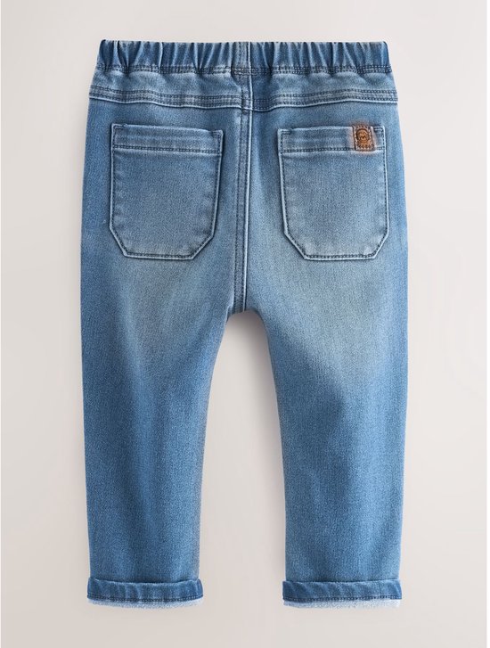 Achterkant van lichtblauwe denim jeans met twee opgestikte zakken, elastische tailleband en opgerolde zoom.