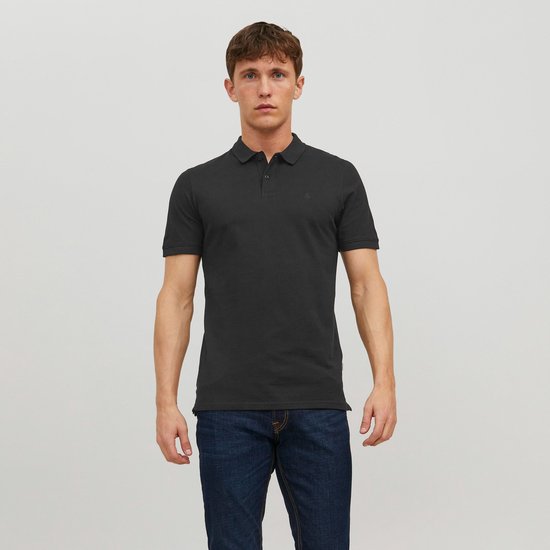 Man met donkere polo met korte mouwen en een kraag, staand