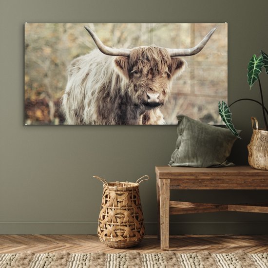 Sfeervol interieur met een Schotse Hooglander glasschilderij boven een houten bankje.