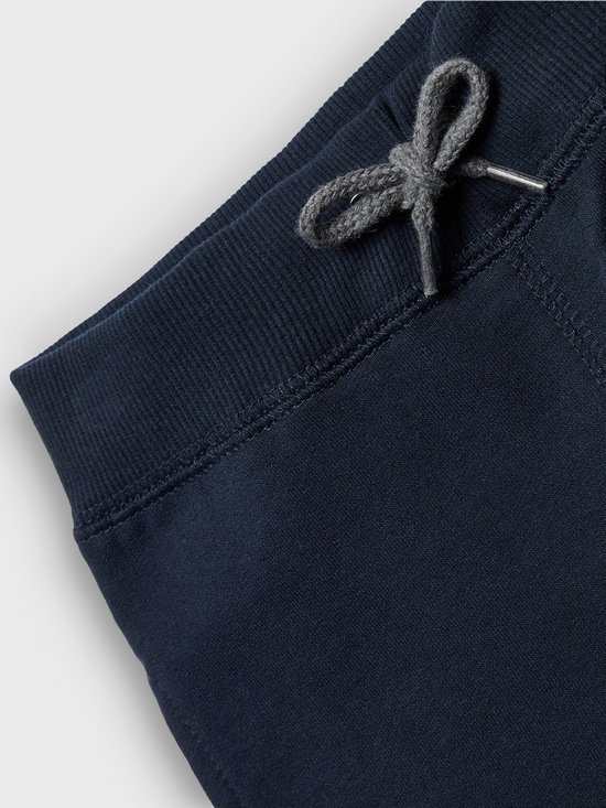 Sluiting van navy joggingbroek met grijze veter en metalen oogjes.