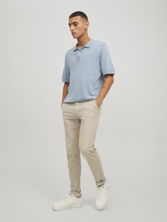 Man in lichtblauwe polo en beige chino.