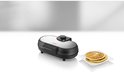 Zwarte Unold pancakemaker met RVS deksel, een stapel pancakes op een wit bord.
