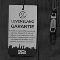 Close-up van een TRVLMORE rugzaklabel met levenslange garantie en een rits met 'TRVLMORE' erop.