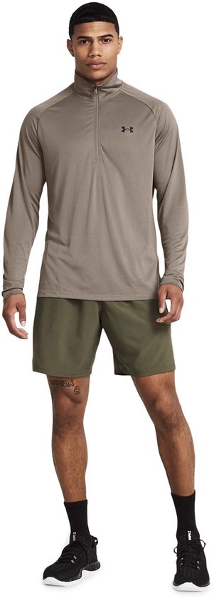 Man met lange mouwen, grijze halve rits trui en legergroene shorts