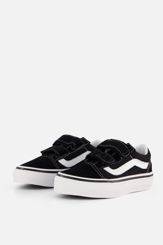 Twee zwarte Vans Old Skool V sneakers met witte wavy streep en klittenbandsluitingen, op een lichte achtergrond.