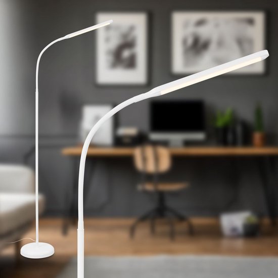 Witte staande lamp in een woonkamer, voor een bureau met computer en schilderijen aan de muur.