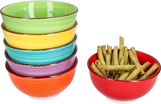 Gestapelde kleurrijke kommetjes in groen, geel, blauw, paars en oranje, naast een rood kommetje gevuld met snacks.