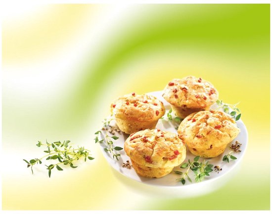 Vier hartige muffins met stukjes tomaat en kruiden op een wit bord, gegarneerd met takjes tijm.