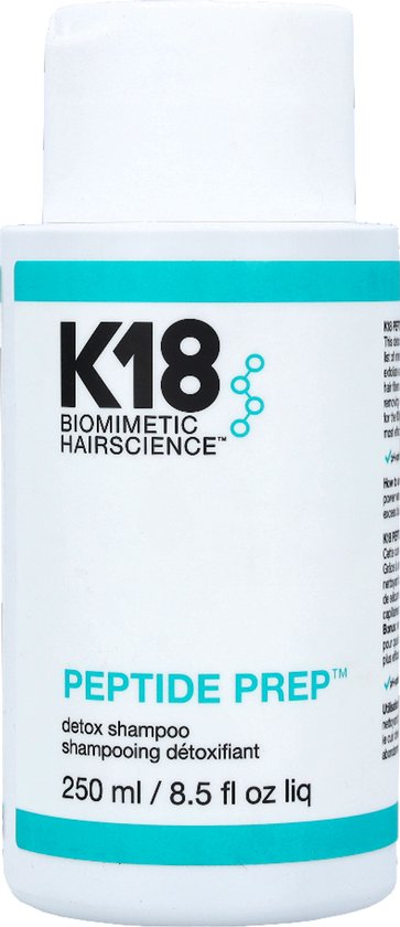 Witte K18 Peptide Prep Detox Shampoo fles met turquoise banden en zwarte tekst, met extra productinfo op de zijkant.