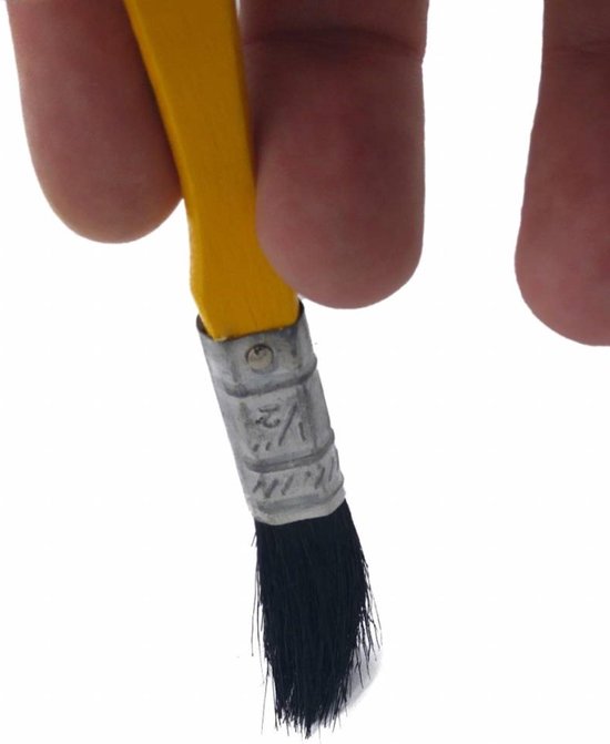 Close-up van een hand die een kleine platte kwast vasthoudt. Geel handvat met rode punt, zilveren metalen band.