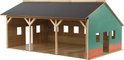 Houten landbouwloods met groene zijkanten en rode bakstenen accenten. Grote open voorkant.