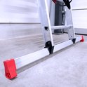 Detail van de rode, gekartelde stabilisatorvoeten aan de onderkant van een aluminium ladder.