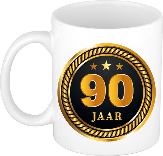 Witte mok met gouden medaille-opdruk "90 JAAR" en drie sterren.