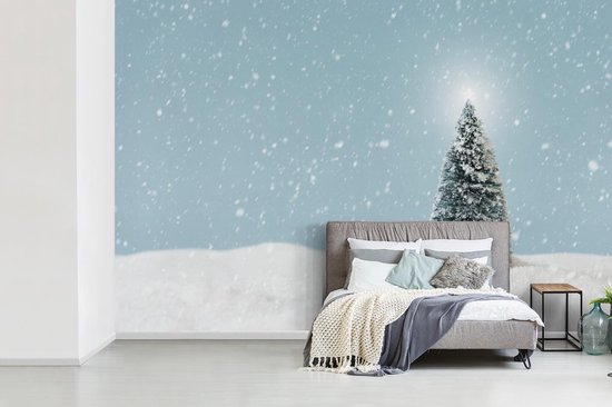 Behang - Fotobehang Een kerstboom in een besneeuwd landschap en een blauwe hemel - Breedte 525 cm x hoogte 350 cm