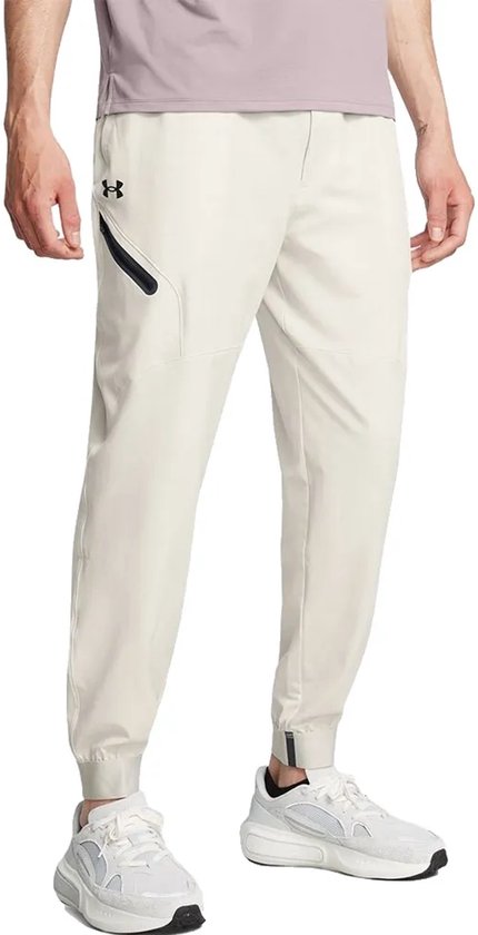 Man met beige joggingbroek, zijkant, met zwarte accenten en witte sneakers.