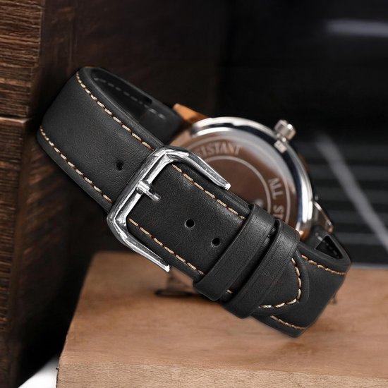 Bracelet de montre en cuir de veau noir avec coutures beiges, boucle argentée, attaché à une montre.