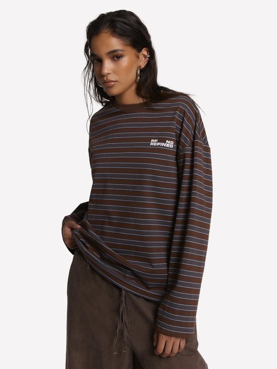 Model draagt een bruin gestreept longsleeve t-shirt met blauwe lijnen en wit 'REFINED' logo op de borst.