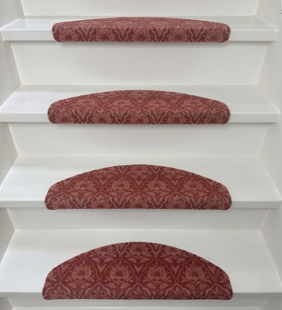 Halve maanvormige trapmatten in rood met bloemig damastpatroon op witte treden.