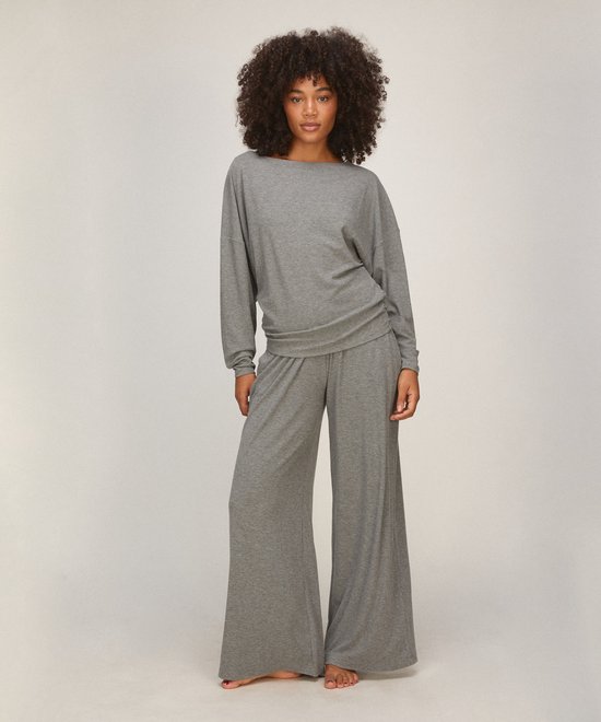 Model draagt een grijze loungewear set bestaande uit een top met vleermuismouwen en een wijdvallende broek.