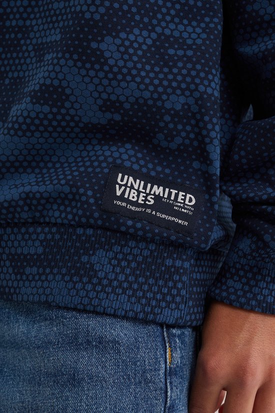 Detail van de zwarte patch op een blauwe hoodie met de tekst 'UNLIMITED VIBES' en 'YOUR ENERGY IS A SUPERPOWER'.