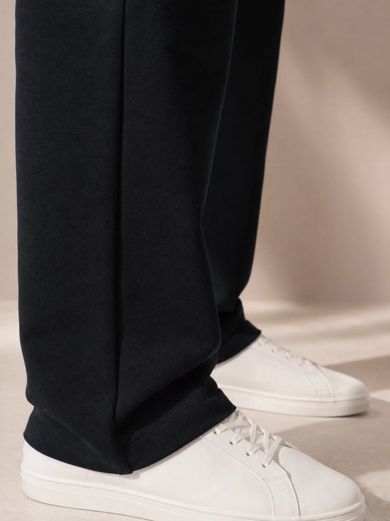 Pantalon de sport bleu marine avec des baskets blanches.