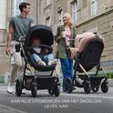 Ouders met twee Kinderkraft wandelwagens in de stad. Tekst: KAN ALLE UITDAGINGEN VAN HET DAGELIJKS LEVEN AAN.