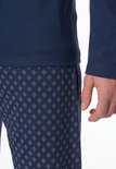 Detailopname van de taille en mouw van de donkerblauwe pyjama met een broek met streeppatroon.