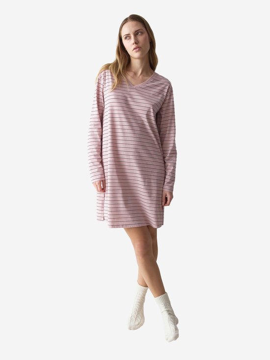 Model in roze nachthemd met lange mouwen en fijne zwarte streepjes, met v-hals. Draagt witte sokken.
