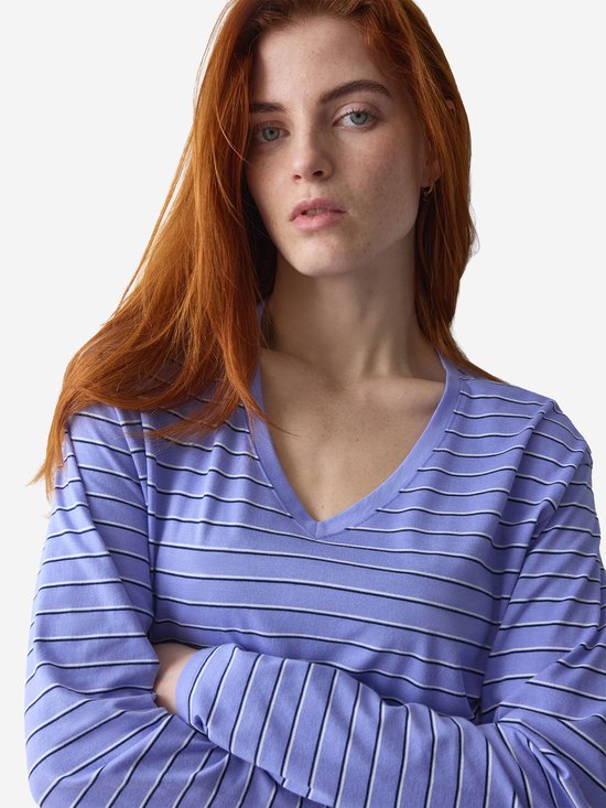 Close-up van model met rood haar in lila gestreept nachthemd met V-hals en gekruiste armen.