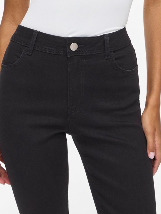Close-up van zwarte skinny jeans met knoopsluiting, riemlussen en voorzakken.