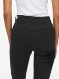 Close-up van de achterkant van een zwarte skinny jeans met zakken en riemlussen.