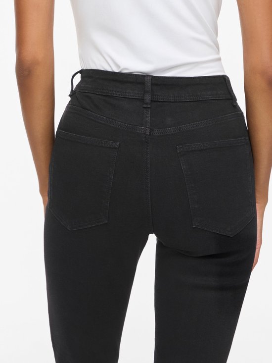 Close-up van de achterkant van een zwarte skinny jeans met zakken en riemlussen.