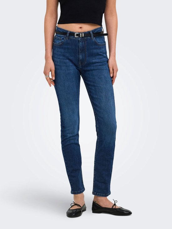 Model draagt een zwarte top en donkerblauwe slim fit jeans met riem, volledige lichaamsopname.