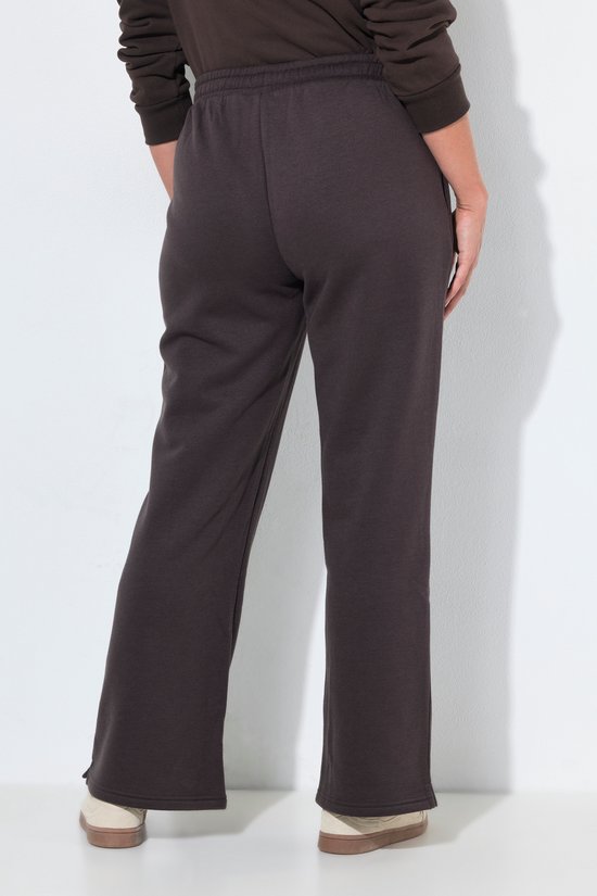 Achteraanzicht van een donkerbruine joggingbroek met wijde pijpen op een model.