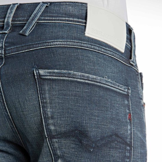 Close-up van de achterzak van een donkerblauwe Replay jeans met wit lederen merklabel.