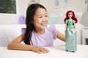Lachend kind speelt met Ariel-pop met rood haar, een tiara en een glinsterende, groen-blauwe jurk met bloemmotieven.