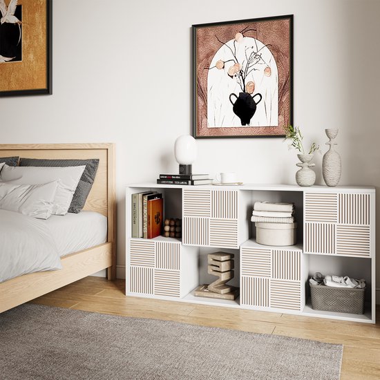 Witte kast in slaapkamer, gevuld met boeken, kleding en decoraties. Sommige vakken hebben een patroon van verticale ribbels.