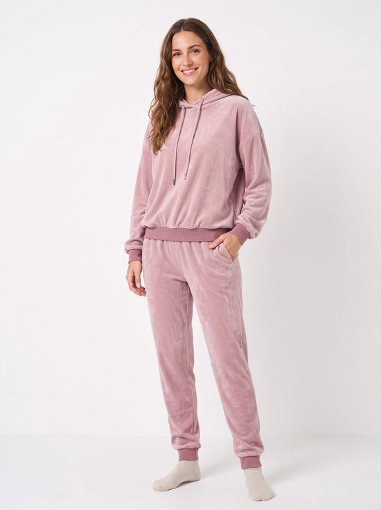 Model draagt een oudroze fleece huispak met hoodie en bijpassende broek met boorden.