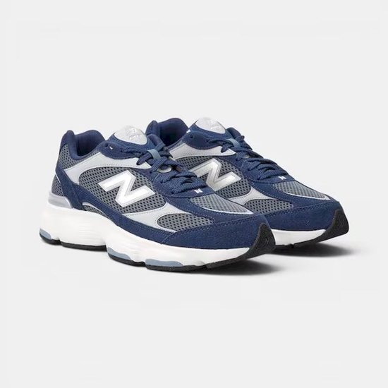 Blauwe New Balance sneakers met witte en grijze accenten en het 'N' logo op de zijkant.