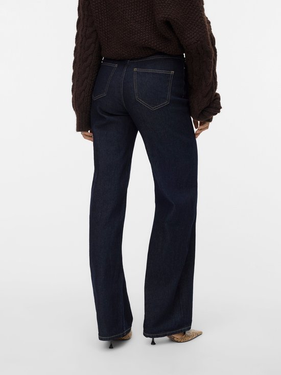Achterkant van een model in donkerblauwe jeans met wijde pijpen en gele stiksels.