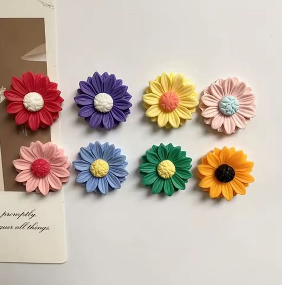 Acht kleurrijke bloemvormige magneten op een witte achtergrond in rood, paars, geel, roze, blauw, groen en oranje.