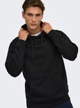 Model houdt de capuchon van een zwarte hoodie vast, zichtbaar met kangoeroezak.