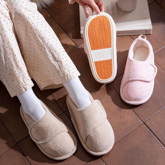 Beige en roze pluche pantoffels met verstelbare klittenbandsluiting, getoond op een model.