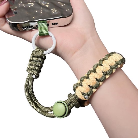 Hand gedragen telefoon met legergroen en beige gevlochten polsbandje bevestigd via een witte ring.