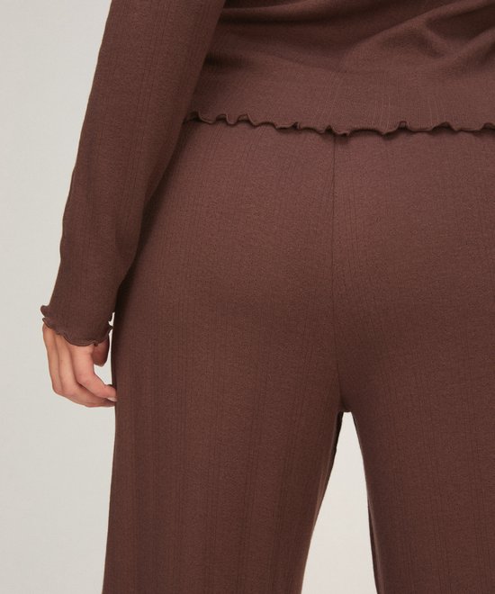 Close-up van de achterkant van een bruine geribbelde pyjamabroek met een golvende zoom aan de broekspijp.