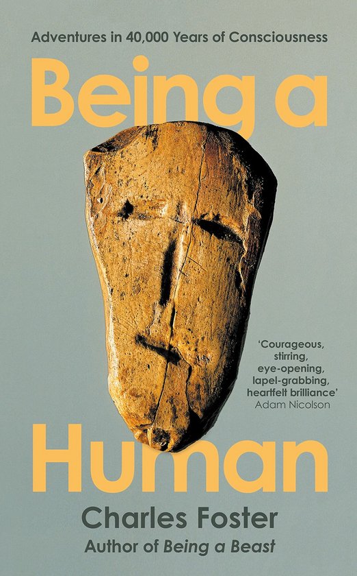 Boekomslag van 'Being a Human' met een oud masker en de tekst 'Adventures in 40,000 Years of Consciousness' en 'Being a Human' door Charles Foster.