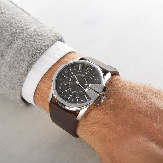Dichtbij-aanzicht van een zilverkleurig Diesel horloge met bruine lederen band op een pols.