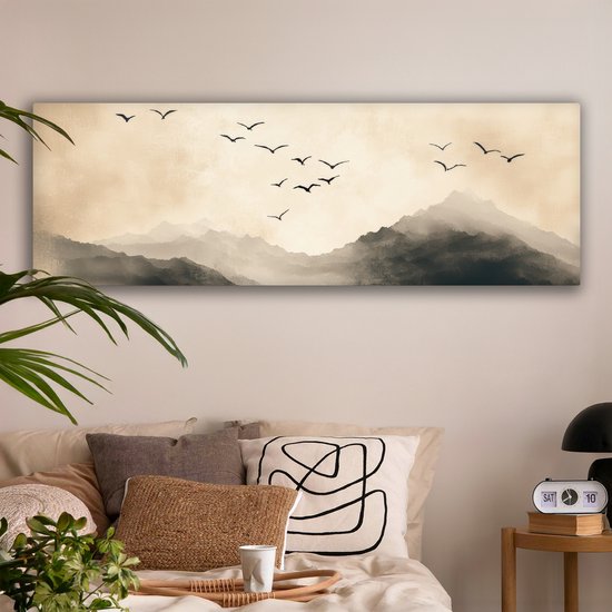 Une toile panoramique avec des montagnes et des oiseaux en vol, dans des tons sépia, au-dessus d'un lit avec des coussins.
