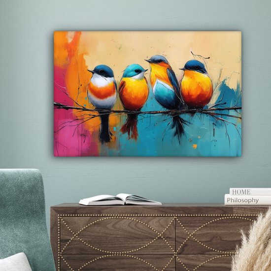 Vier kleurrijke vogels op een tak, hangend aan een muur boven een dressoir. De achtergrond is een abstracte mix van oranje, roze, blauw en geel. Er ligt een boek open op het dressoir.