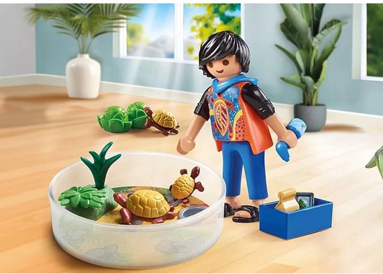 Playmobil jongen met schildpaddenterrarium in een woonkamer. Jongen draagt een oranje vest met een kleurrijk patroon.